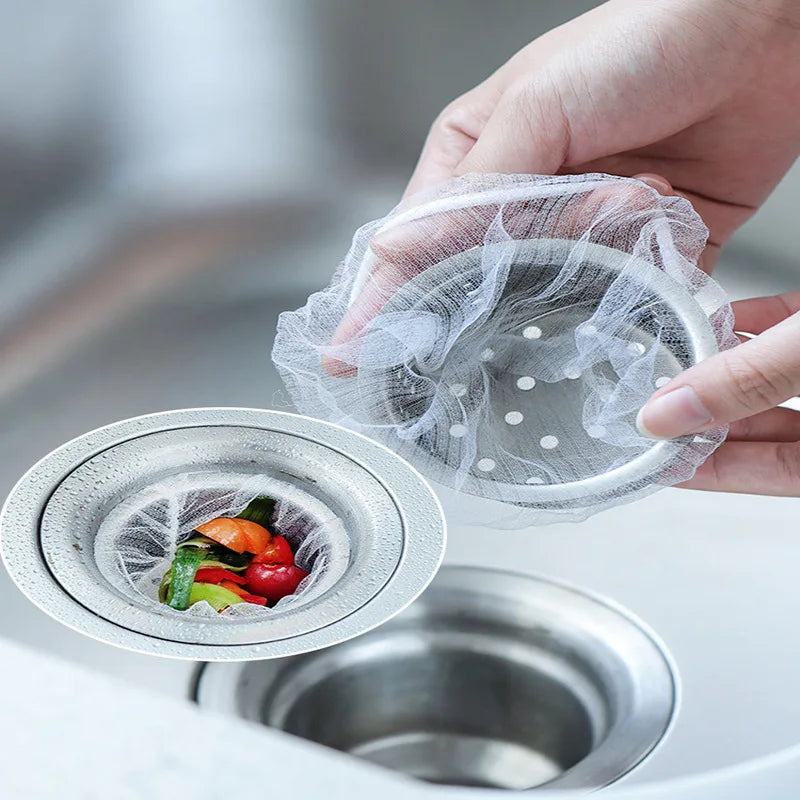 A hand is placing a mesh disposable sink drain filter into a metal sink drain.