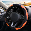 Close-up view of a black steering wheel with an orange accent grip and leather cover inside a car interior.