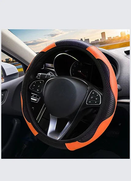 Close-up view of a black steering wheel with an orange accent grip and leather cover inside a car interior.