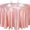 A round pink satin tablecloth set for an elegant table with glassware and silverware.