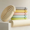 A stack of soft NBR table edge and corner guard bumper strips in various pastel colors, including beige, yellow, pink, mint g