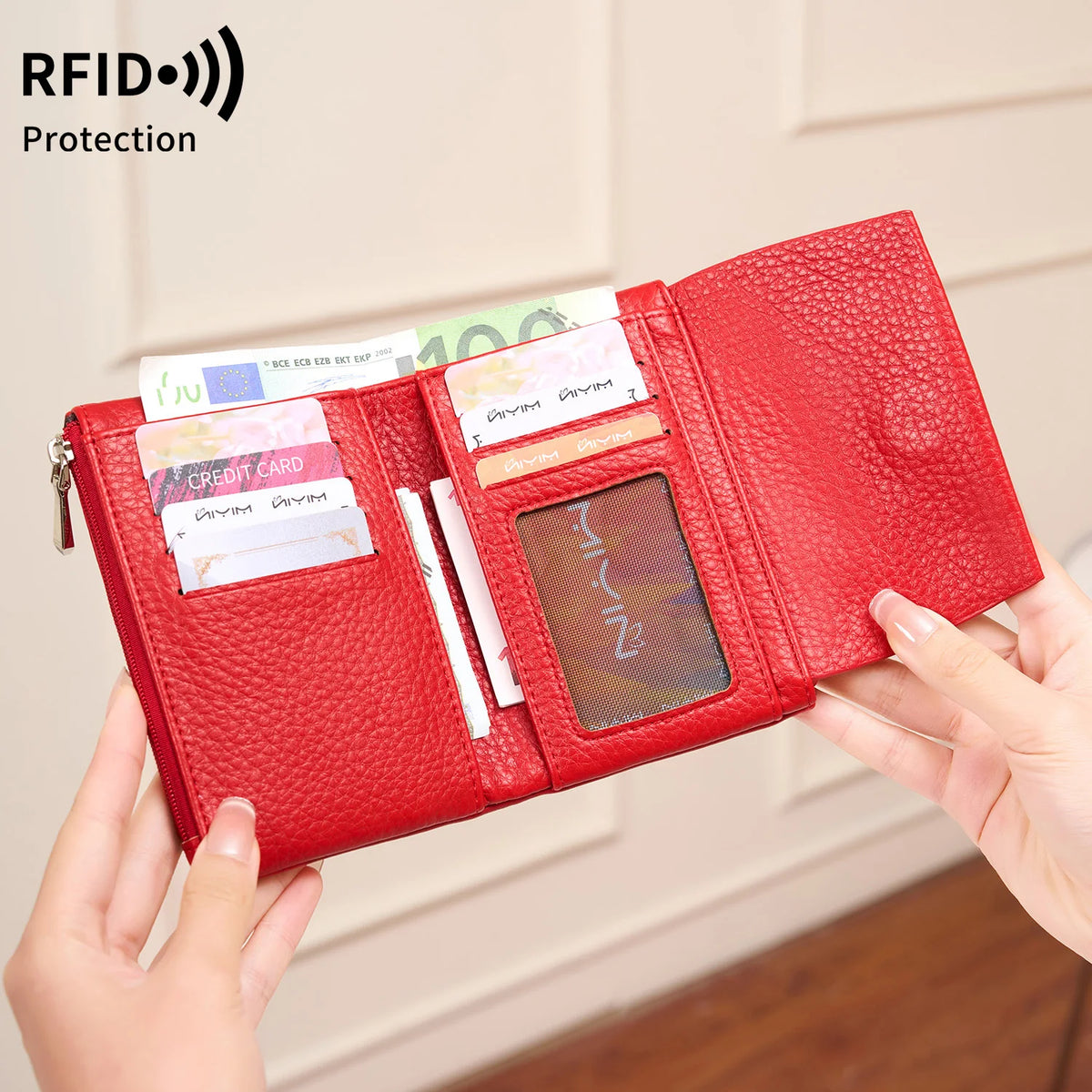 A red RFID-blocking tri-fold wallet with a zipper pocket is shown being held by a hand.