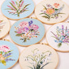 A collection of round embroidery hoops featuring colorful floral designs on light blue and white fabric.