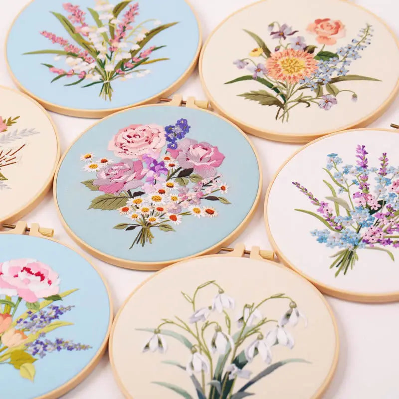 A collection of round embroidery hoops featuring colorful floral designs on light blue and white fabric.