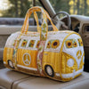 Yellow quilted travel duffle bag with a vintage bus design and stitching resting on a car seat.