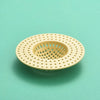 A round, light beige silicone sink drain filter strainer with a perforated mesh design.