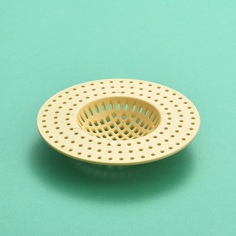 A round, light beige silicone sink drain filter strainer with a perforated mesh design.