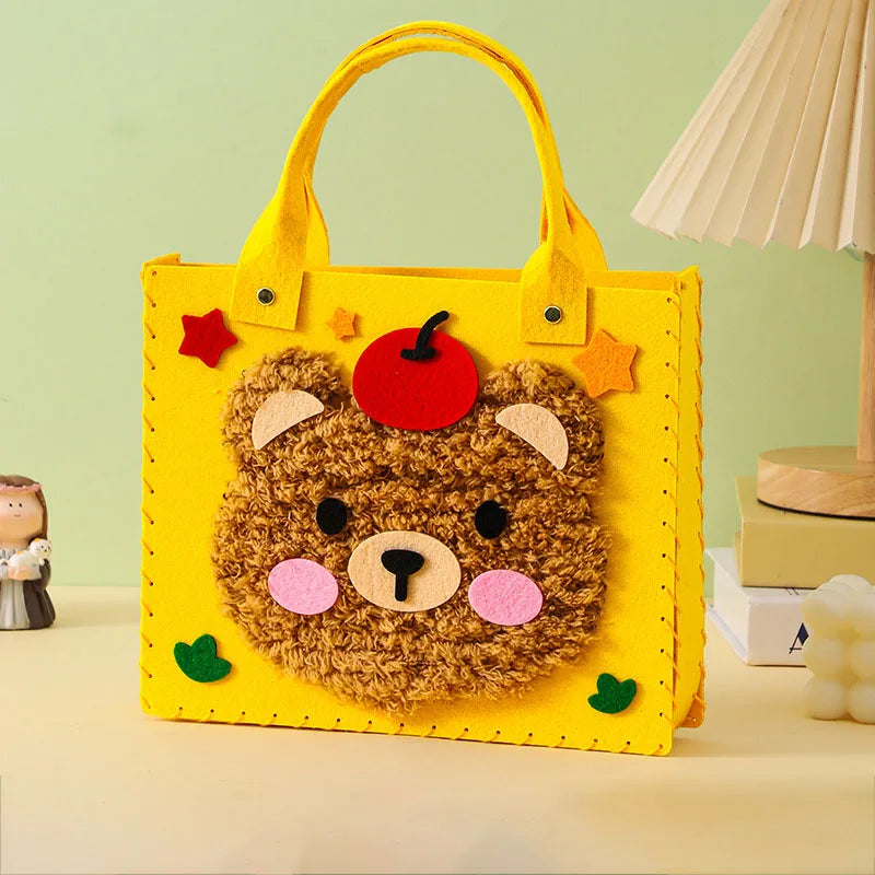 A yellow felt bear-shaped tote bag with orange handles and red accents, used as a DIY craft kit.