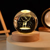 Laser engraved crystal ball night light with a silhouette of a deer on a wooden base