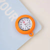 An orange silicone pocket watch with a round face and a small pin is shown on a light blue background.