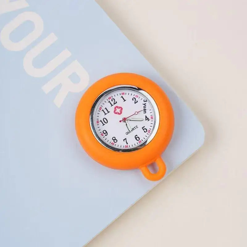 An orange silicone pocket watch with a round face and a small pin is shown on a light blue background.