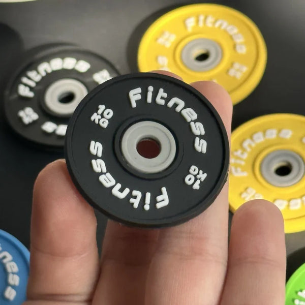A hand holds a black fitness weight plate and a yellow fitness weight plate.