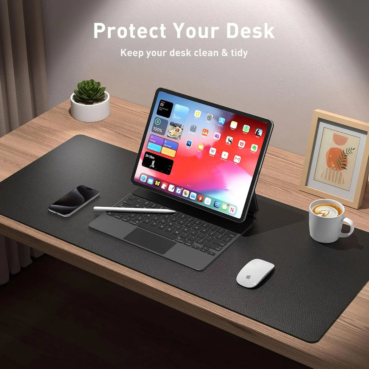A laptop is placed on a black desk pad with a mouse and a coffee cup nearby, emphasizing desk protection.