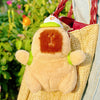 A fluffy brown capybara plush toy is resting on a yellow towel, with a red and white swim ring visible.