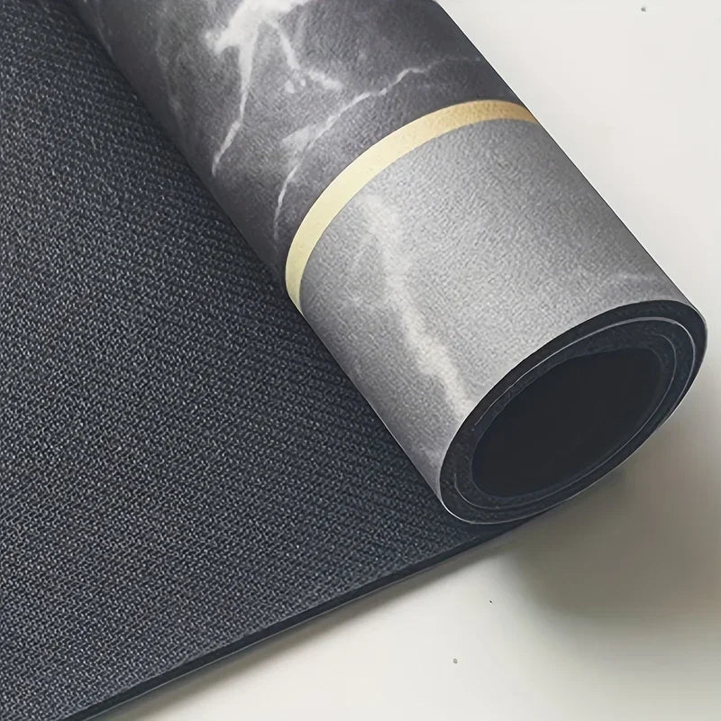 Roll of dark gray diatomite bath mat with a gold accent band lying next to a flat mat.