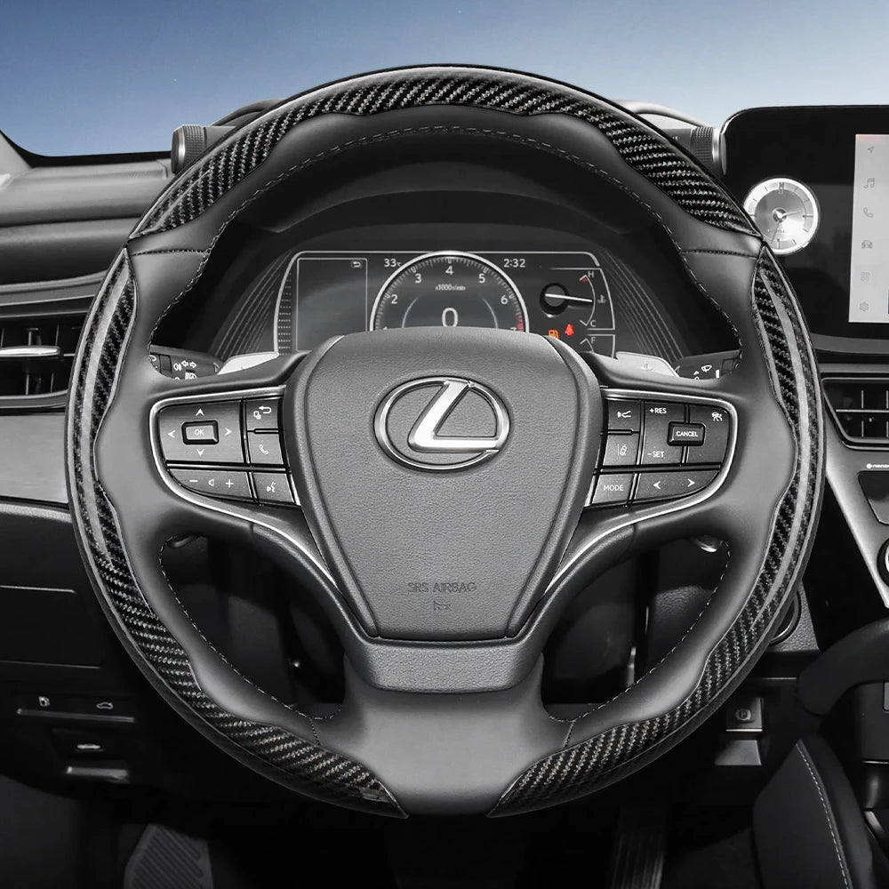 A close-up view of a black steering wheel with carbon fiber texture and controls in a car interior.