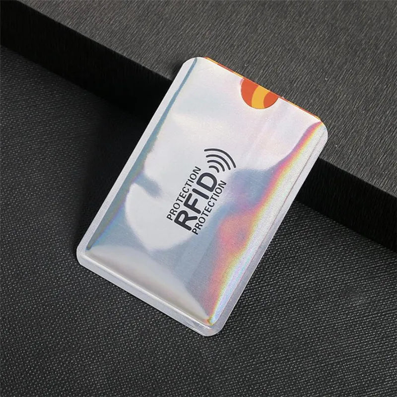 A silver aluminum card holder with an RFID protection symbol is shown on a dark surface.