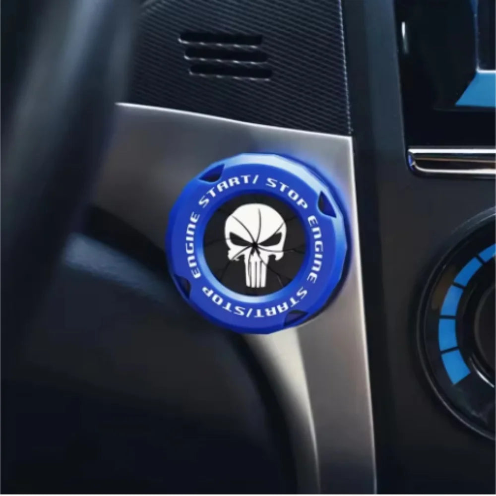 A close-up of a blue rotating protective cover for a car ignition start button featuring a skull design.