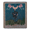 A dark teal woven blanket featuring a starry night sky and pink roses with a coiled black snake.