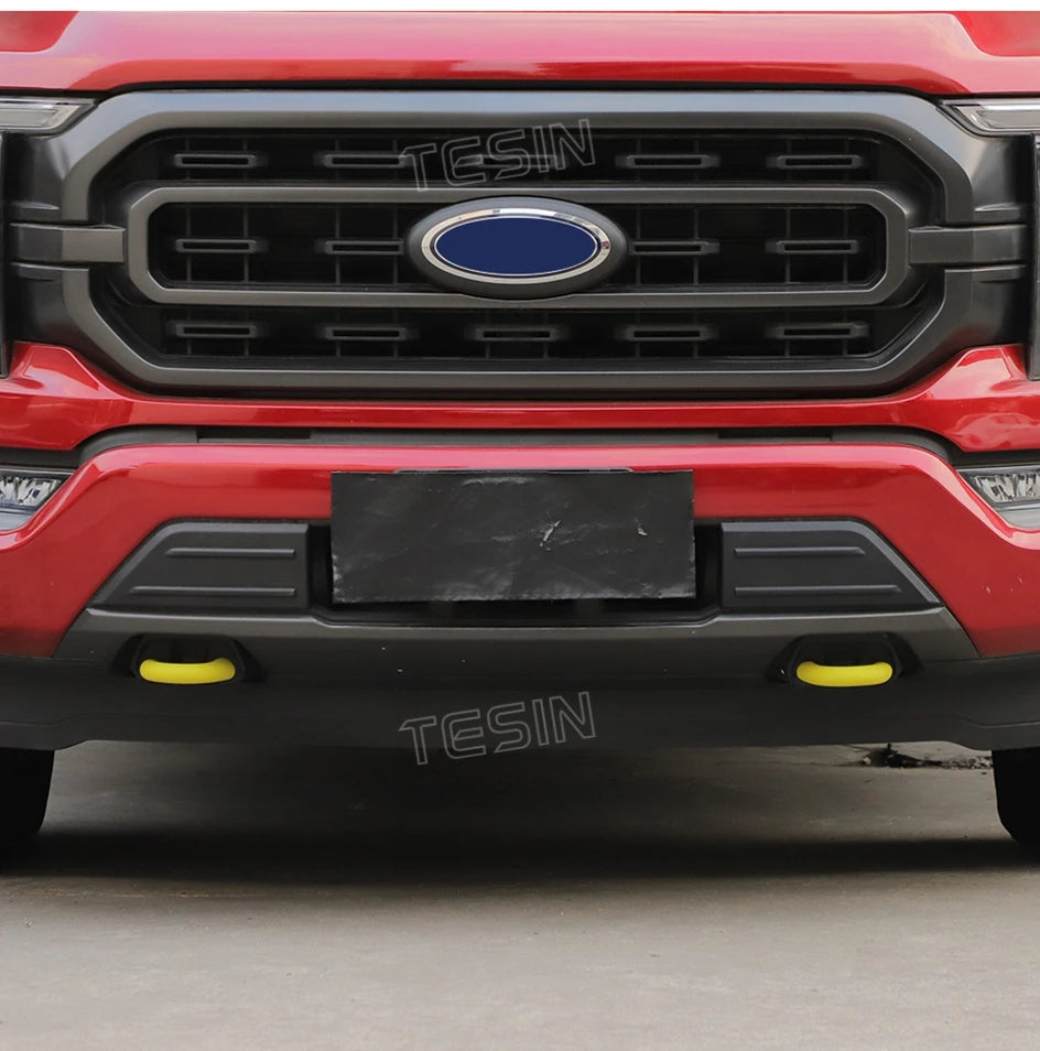 Close-up of a red Ford F-150 front bumper with a black TESIN tow hook cover installed.