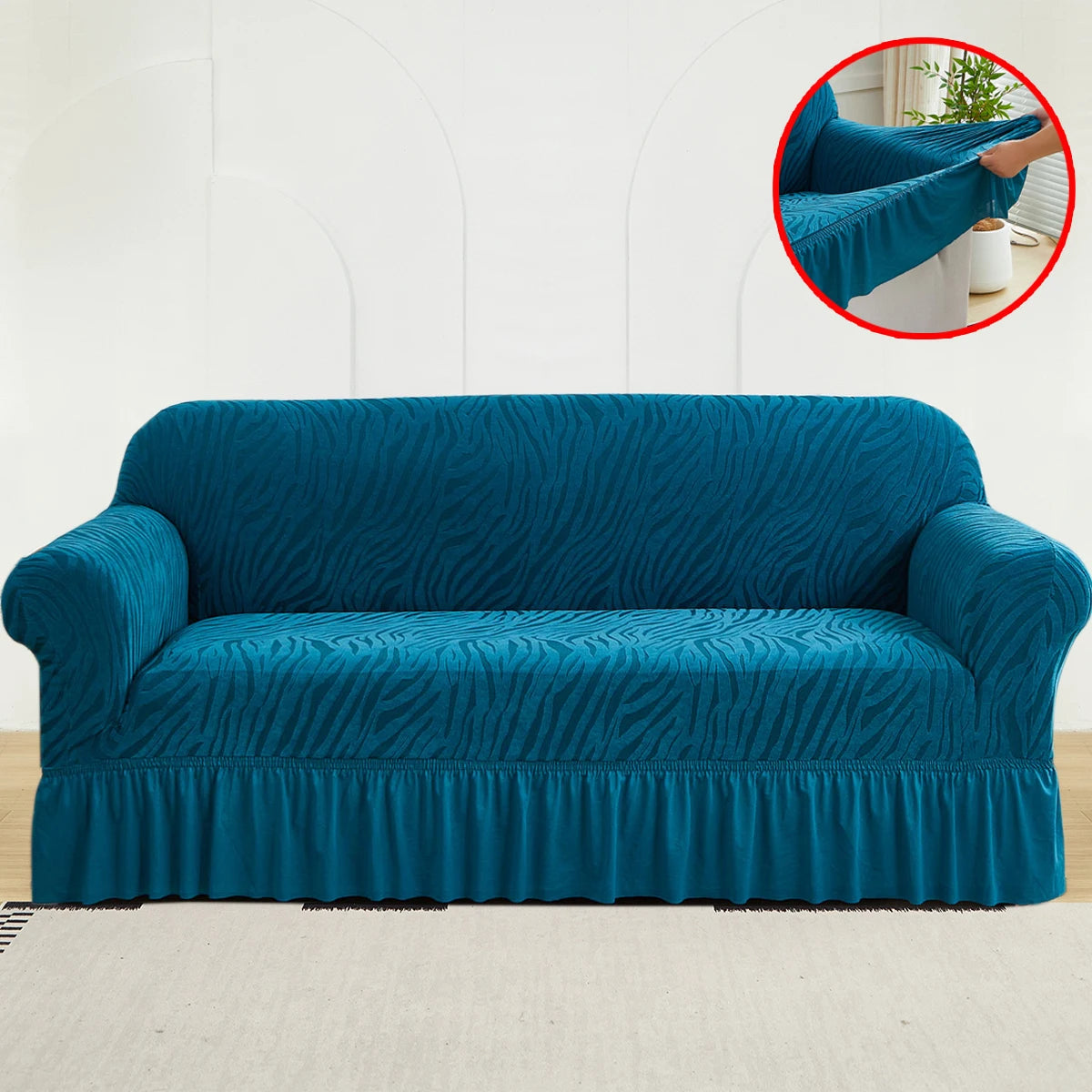 A teal jacquard sofa cover featuring a wave pattern and an elastic skirt, displayed on a light-colored rug.