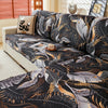 A black and gold floral patterned elastic sofa cover draped over a light-colored sofa.