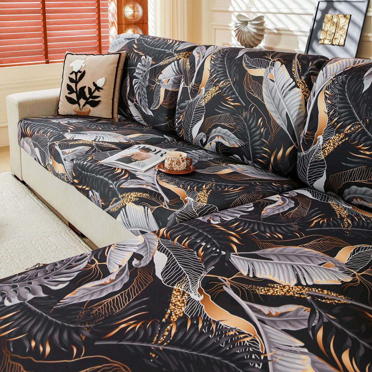 A black and gold floral patterned elastic sofa cover draped over a light-colored sofa.