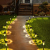 A pathway lined with solar powered garden lantern lights leading toward a house entrance.