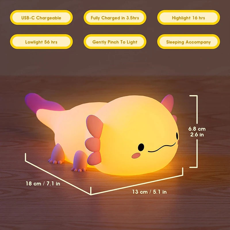 A glowing yellow axolotl night light with pink accents resting on a wooden surface.