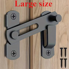 A close-up view of a large stainless steel flip barn door lock mechanism with keys installed on a wooden surface.