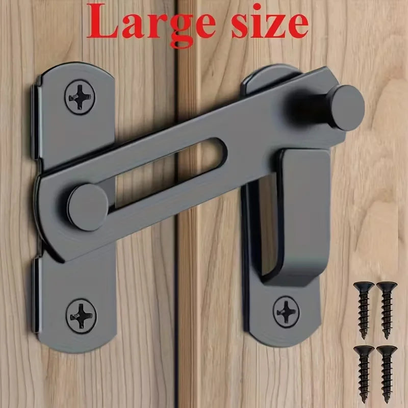 A close-up view of a large stainless steel flip barn door lock mechanism with keys installed on a wooden surface.
