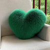 A vibrant green plush heart-shaped throw pillow resting on a light-colored sofa.