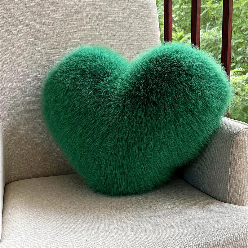 A vibrant green plush heart-shaped throw pillow resting on a light-colored sofa.