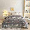 A gray plush throw blanket with white bear patterns is displayed on a bed, next to a wall sign and a white nightstand.