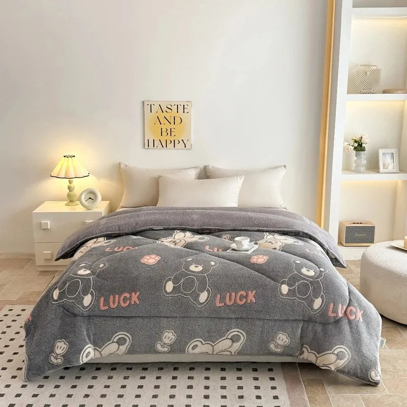 A gray plush throw blanket with white bear patterns is displayed on a bed, next to a wall sign and a white nightstand.