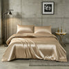 A luxurious champagne silk duvet cover set displayed on a bed in a modern, industrial-style room.