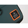 A close-up of a dark green water-resistant crossbody bag with an orange patch featuring the WANLIU logo.