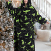 A woman wearing an oversized black hoodie blanket with green dinosaur print in a brightly lit interior.