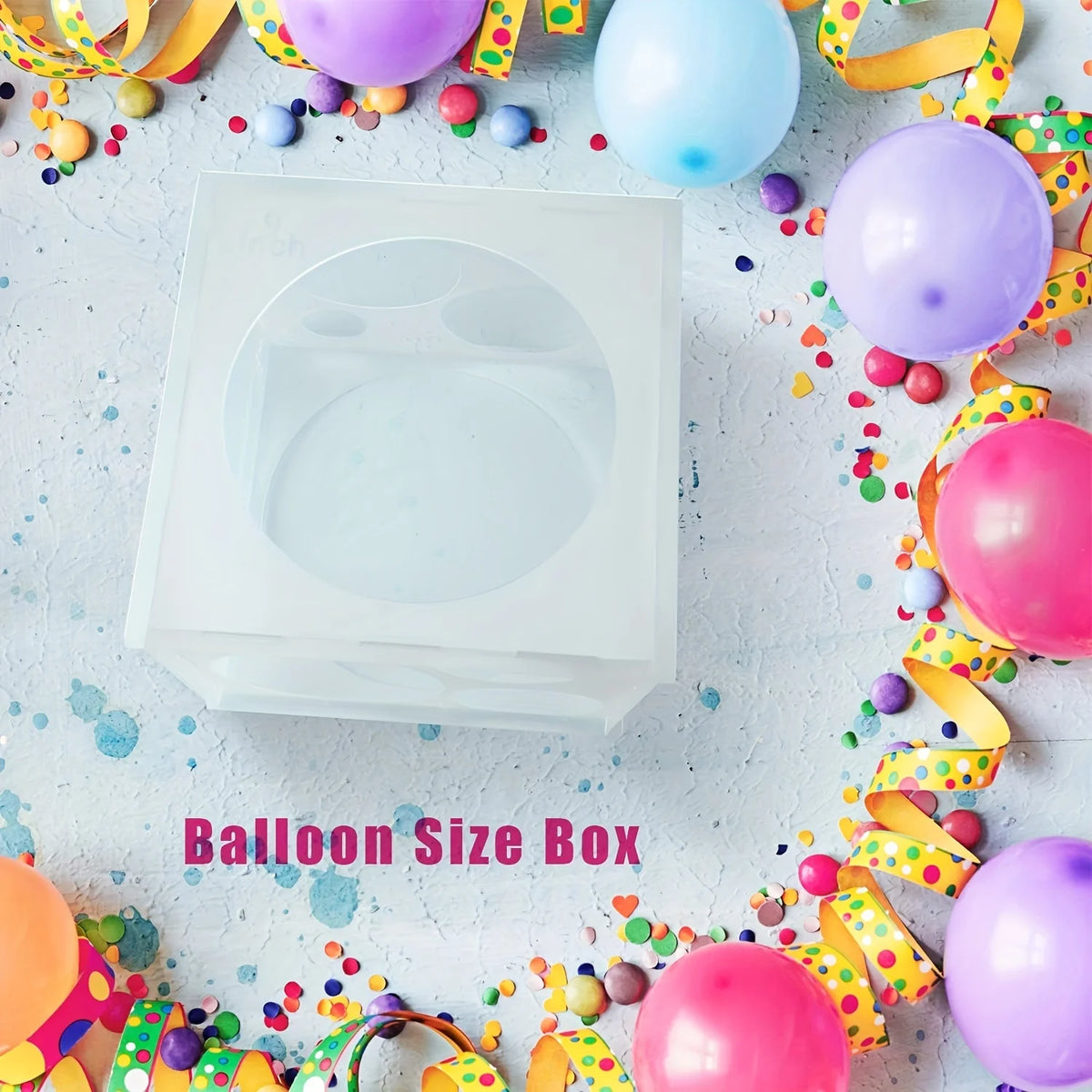 A white collapsible balloon sizer cube with multiple sizing holes surrounded by colorful confetti and balloons.