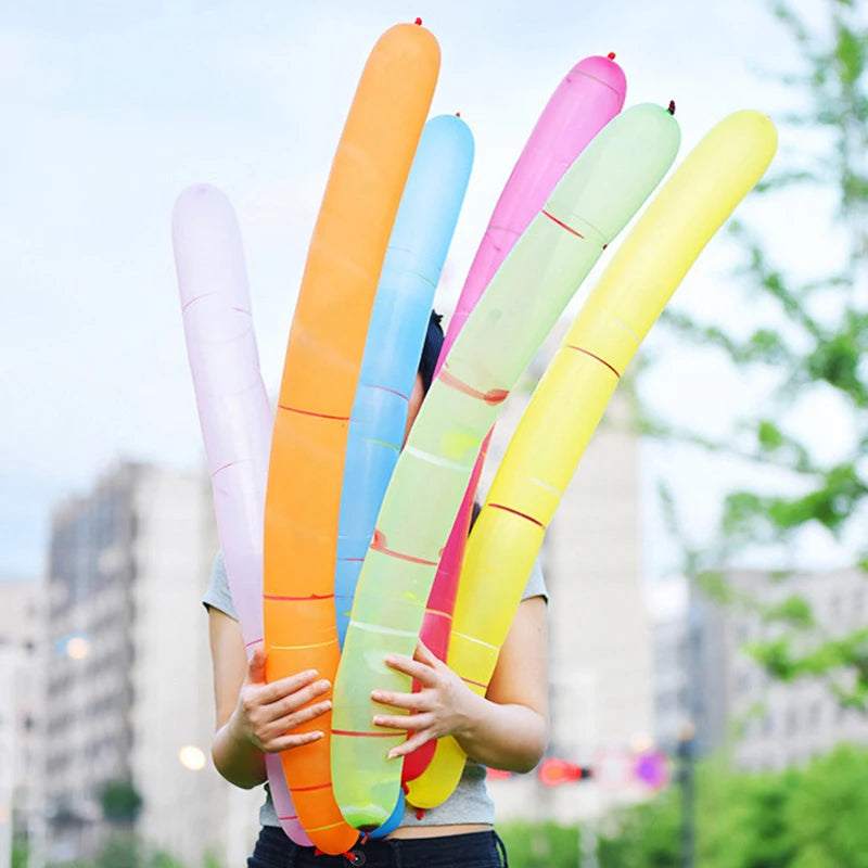 A person holds a bunch of colorful whistling flying party balloons, including orange, pink, blue, and yellow.