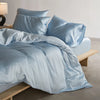 Light blue luxury mulberry silk duvet cover set with pillows and bedding on a bed.
