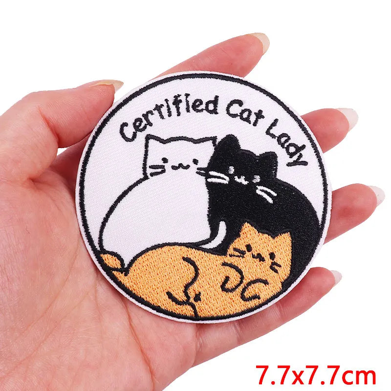 A round embroidery patch featuring a black cat sitting on an orange cat, with text reading Certified Cat Lady.