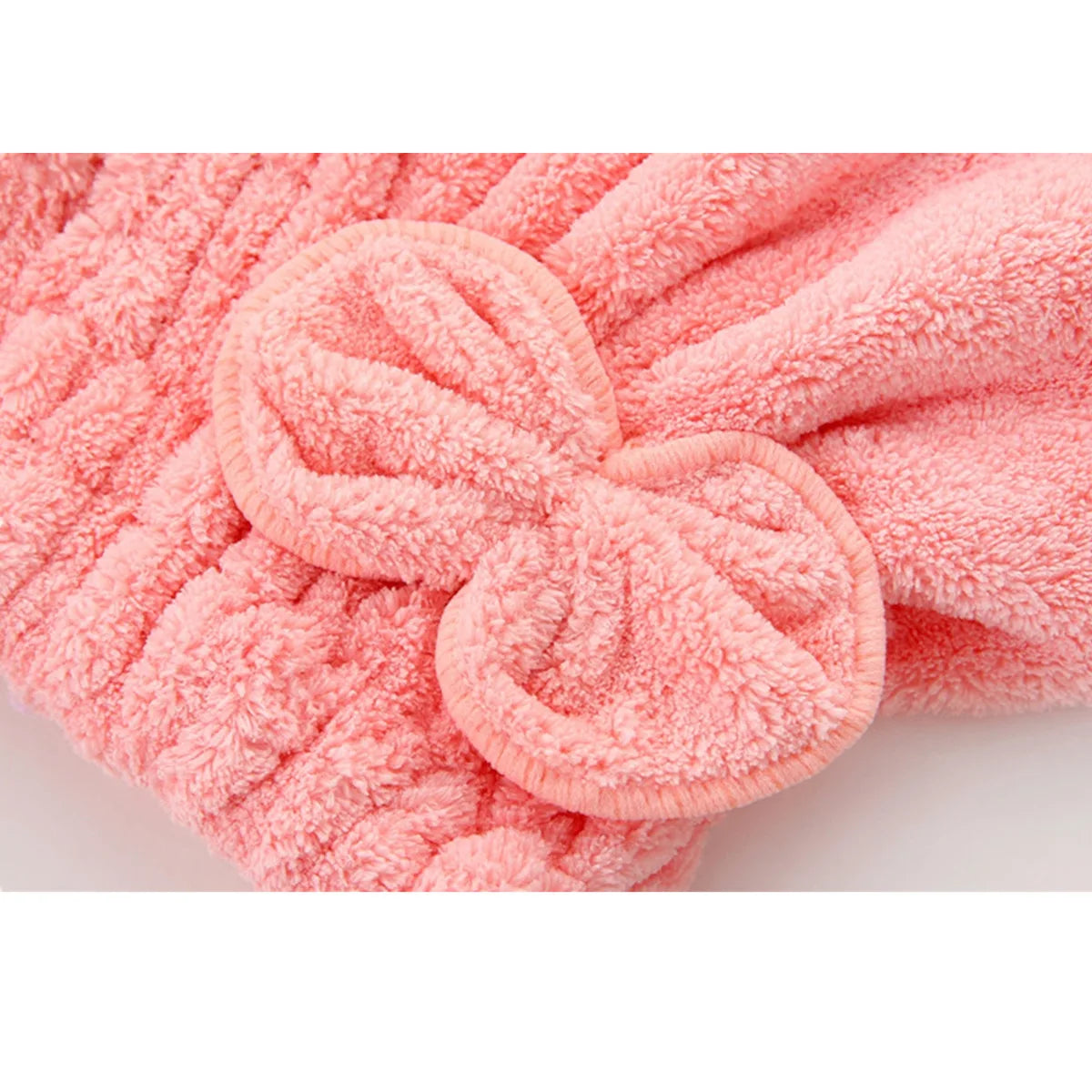 A pink microfiber hair drying towel with a bow-knot head wrap texture.