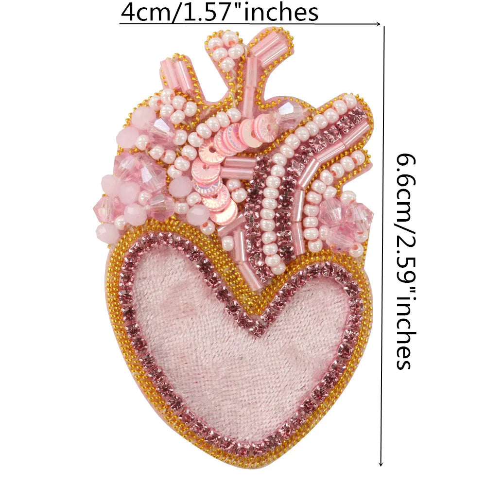 A heart-shaped patch made of pink and clear beads and rhinestones for clothing or crafts.