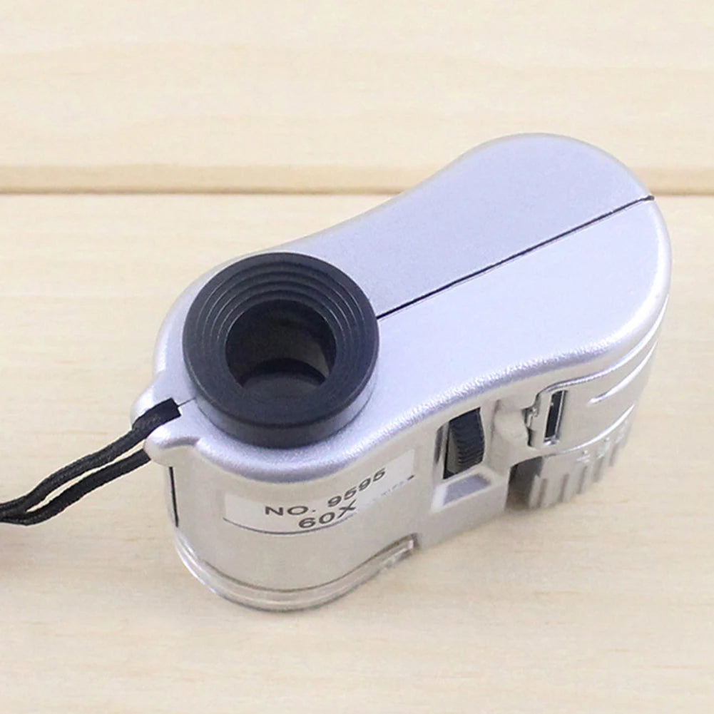 Silver handheld magnifier with a lens and storage pouch labeled NO. 9595 60X