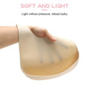 A hand is holding a light beige silicone baby bib with a catch pocket, demonstrating its soft and light design.