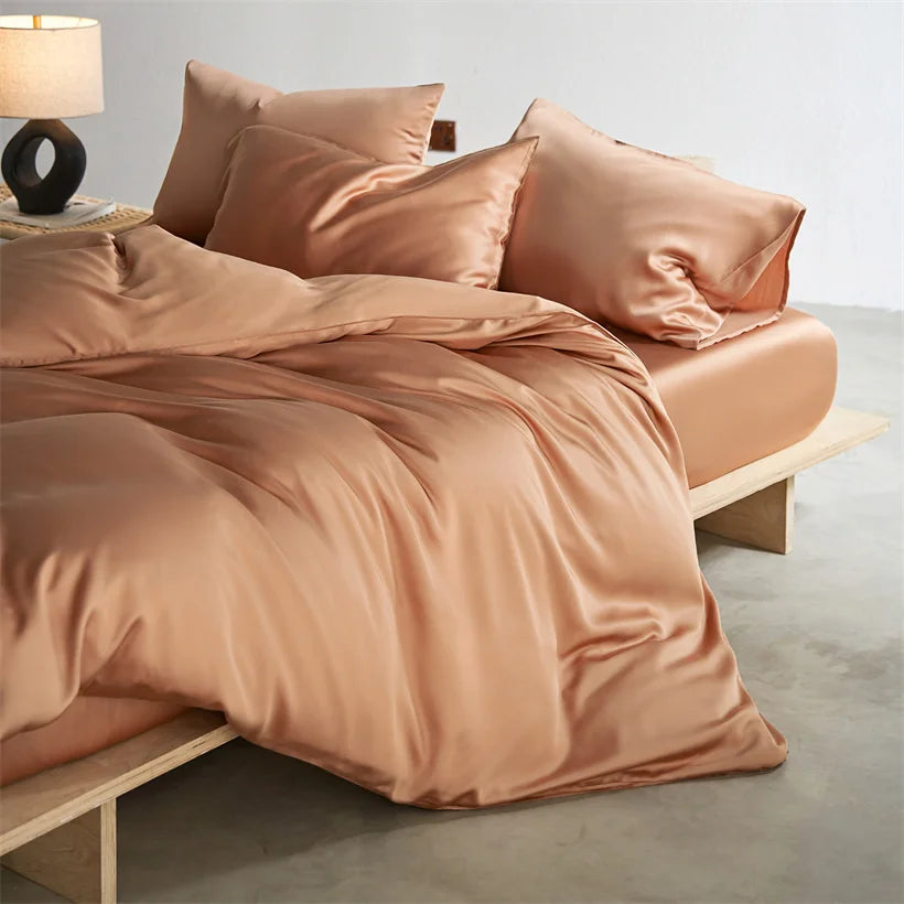 A set of luxurious rose gold silk duvet covers and pillows on a bed.