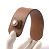 A brown genuine leather handbag handle wrap and shoulder pad being held by a hand.