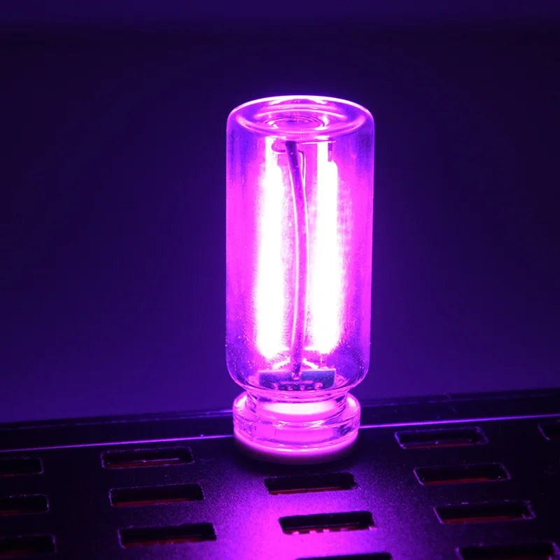 A glowing purple glass accent light bulb is placed on a black grid surface.