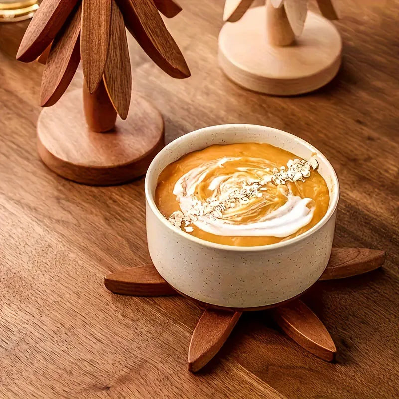 A ceramic bowl filled with orange-colored soup or puree is displayed on a wooden trivet set.